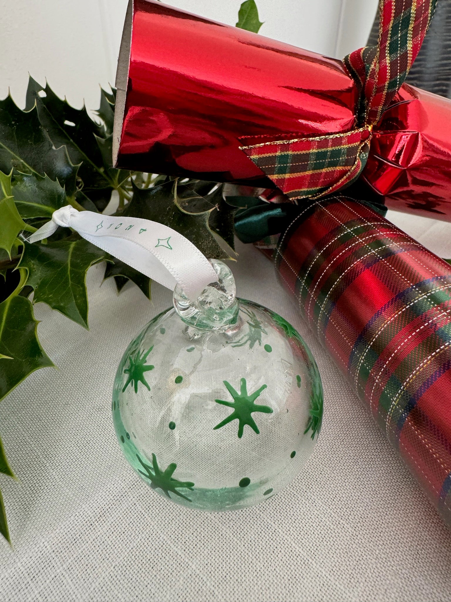 Clear recycled glass painted with green stars hanging on white ribbon.  handmade in Bethlehem